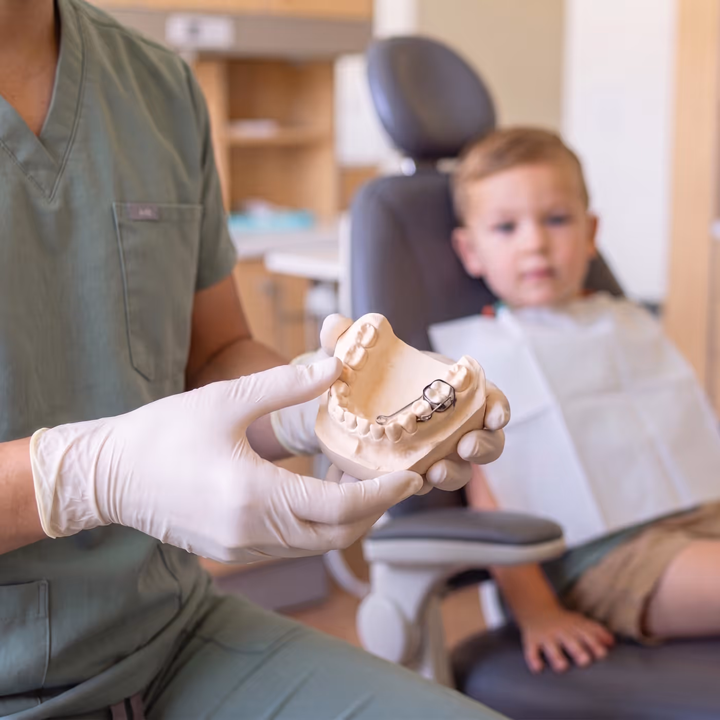 A space maintainer on a plaster model, shown to a child in the treatment chair