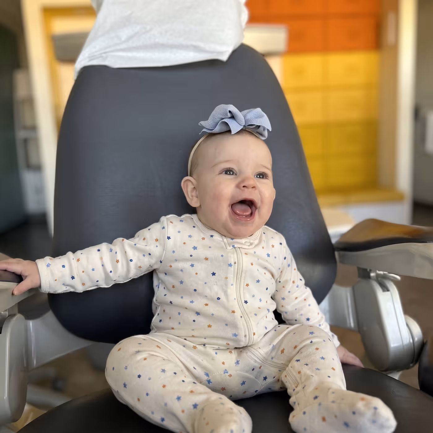 A happy baby sitting in the dental chair before a tongue and lip tie assessment